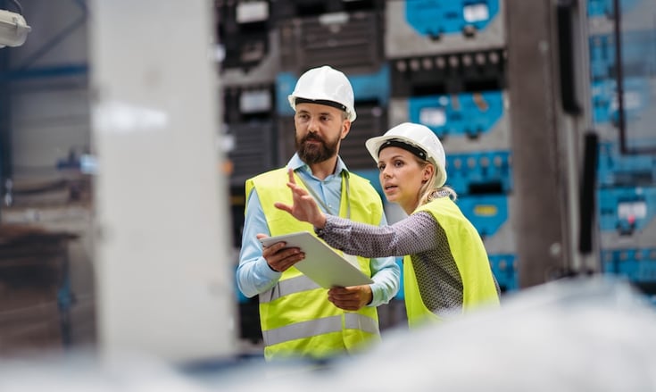 two people in a manufacturing facility evaluating how a robot would work in this environment