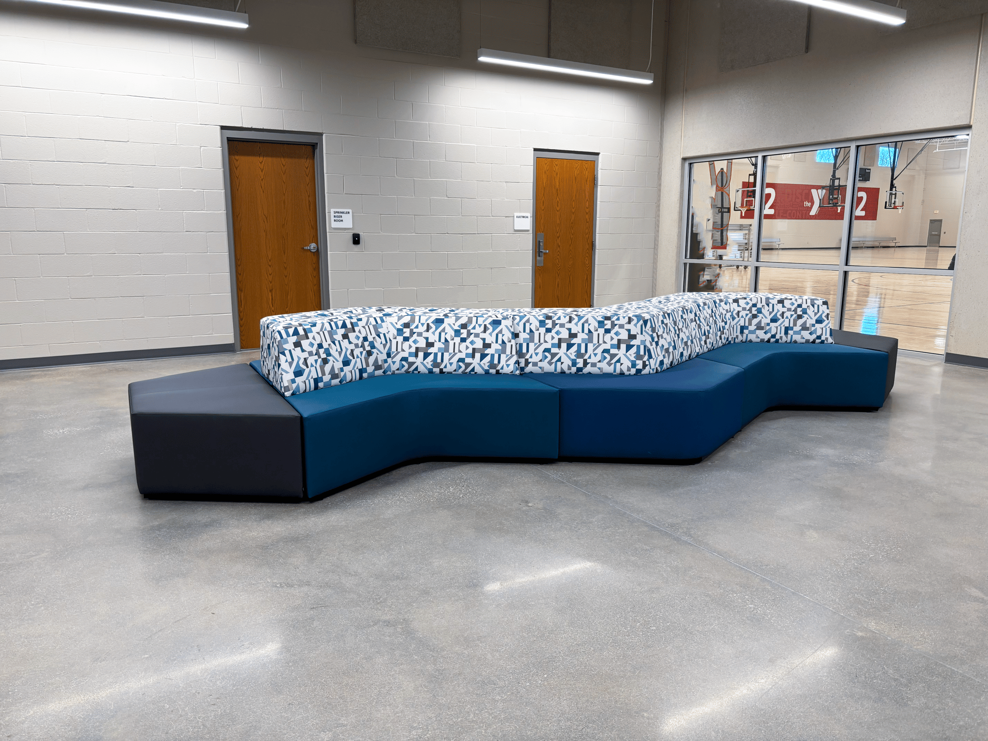 Zig-zag couch next to windows showing a basketball court Zig-zag couch next to windows showing a basketball court