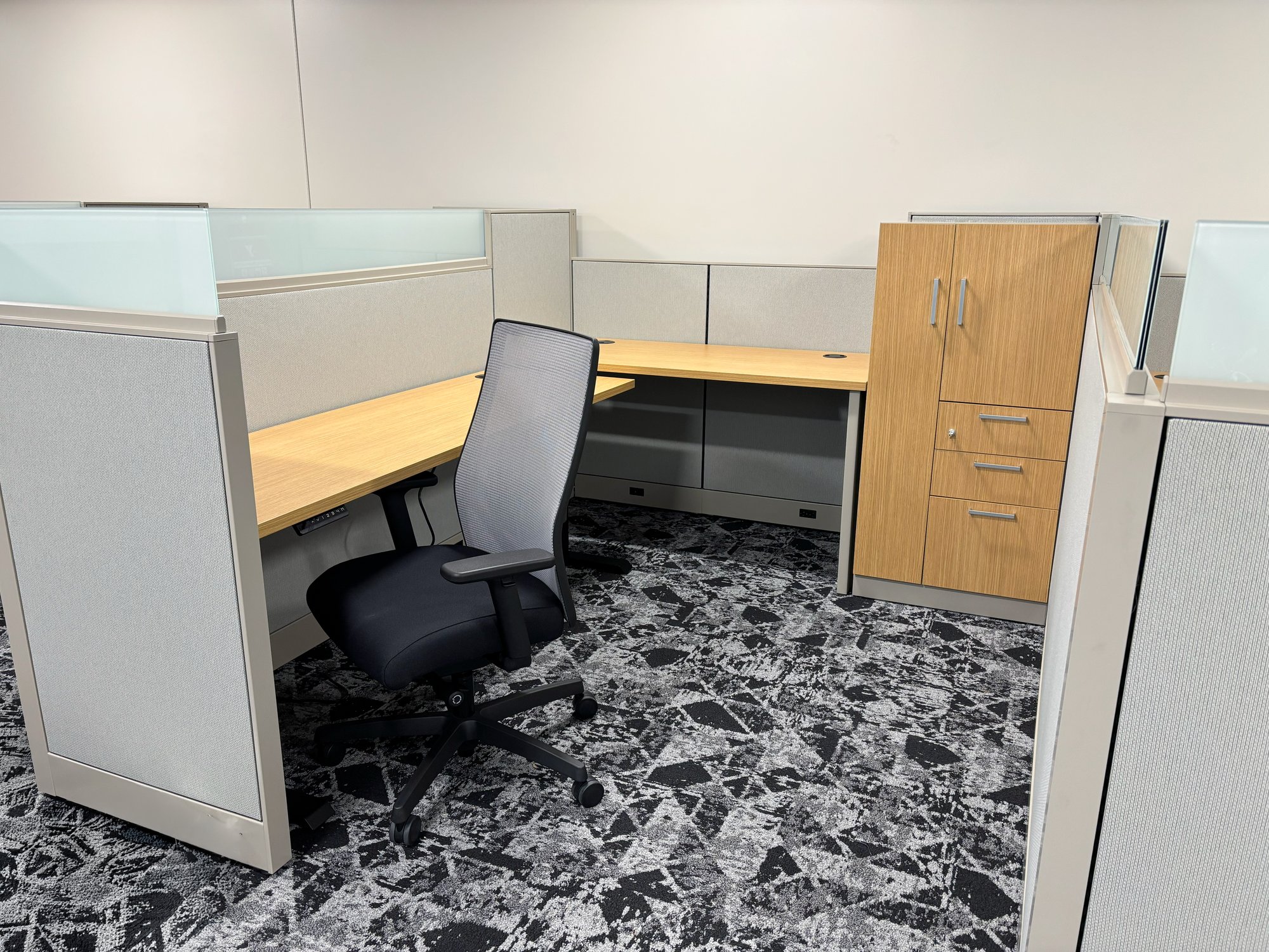 Cubicle with built-in storage and a height-adjustable, L-shaped desk Cubicle with built-in storage and a height-adjustable, L-shaped desk