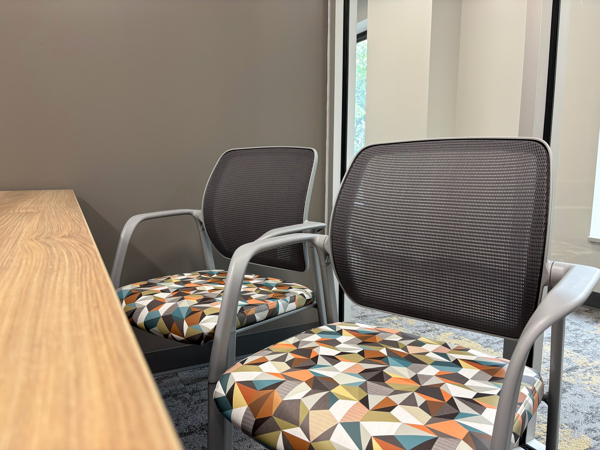 Two rolling guest chairs with a multi-color cushion Two rolling guest chairs with a multi-color cushion