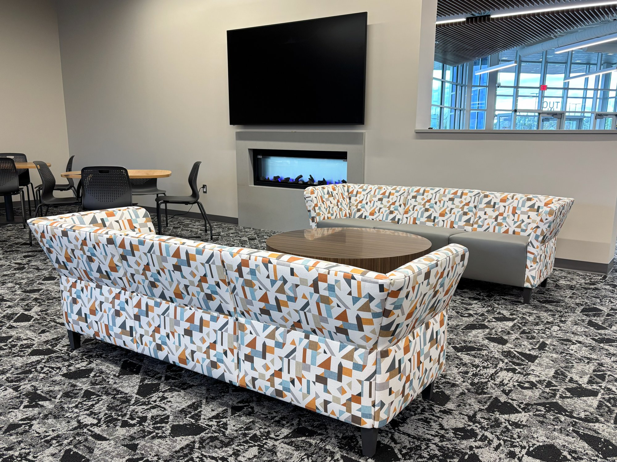 Two multi-color couches sit in front of a fireplace with a TV mounted above it Two multi-color couches sit in front of a fireplace with a TV mounted above it