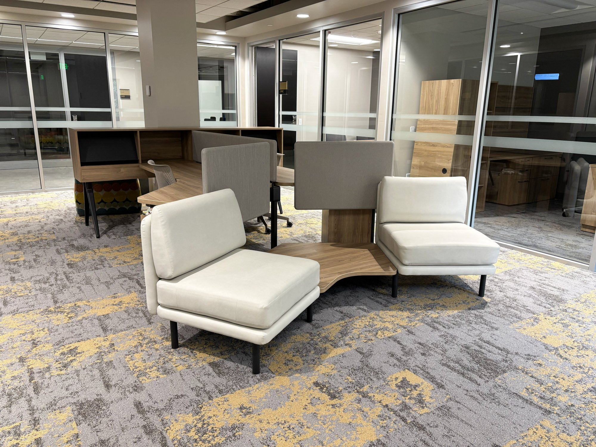 A complex lounge piece with chairs, desks, and privacy partitions A complex lounge piece with chairs, desks, and privacy partitions