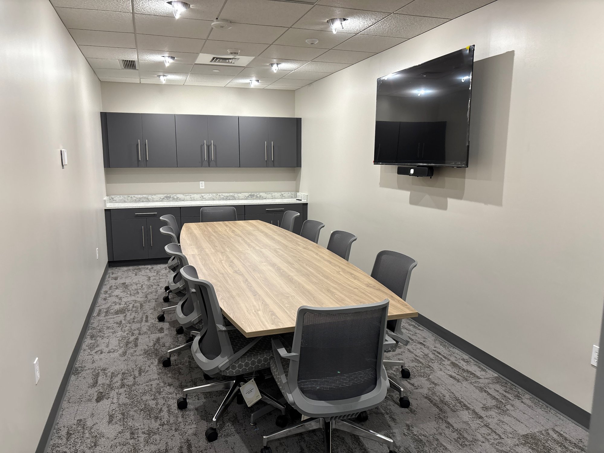 Grey rolling chairs around a boat-shaped conference table in a meeting room Grey rolling chairs around a boat-shaped conference table in a meeting room