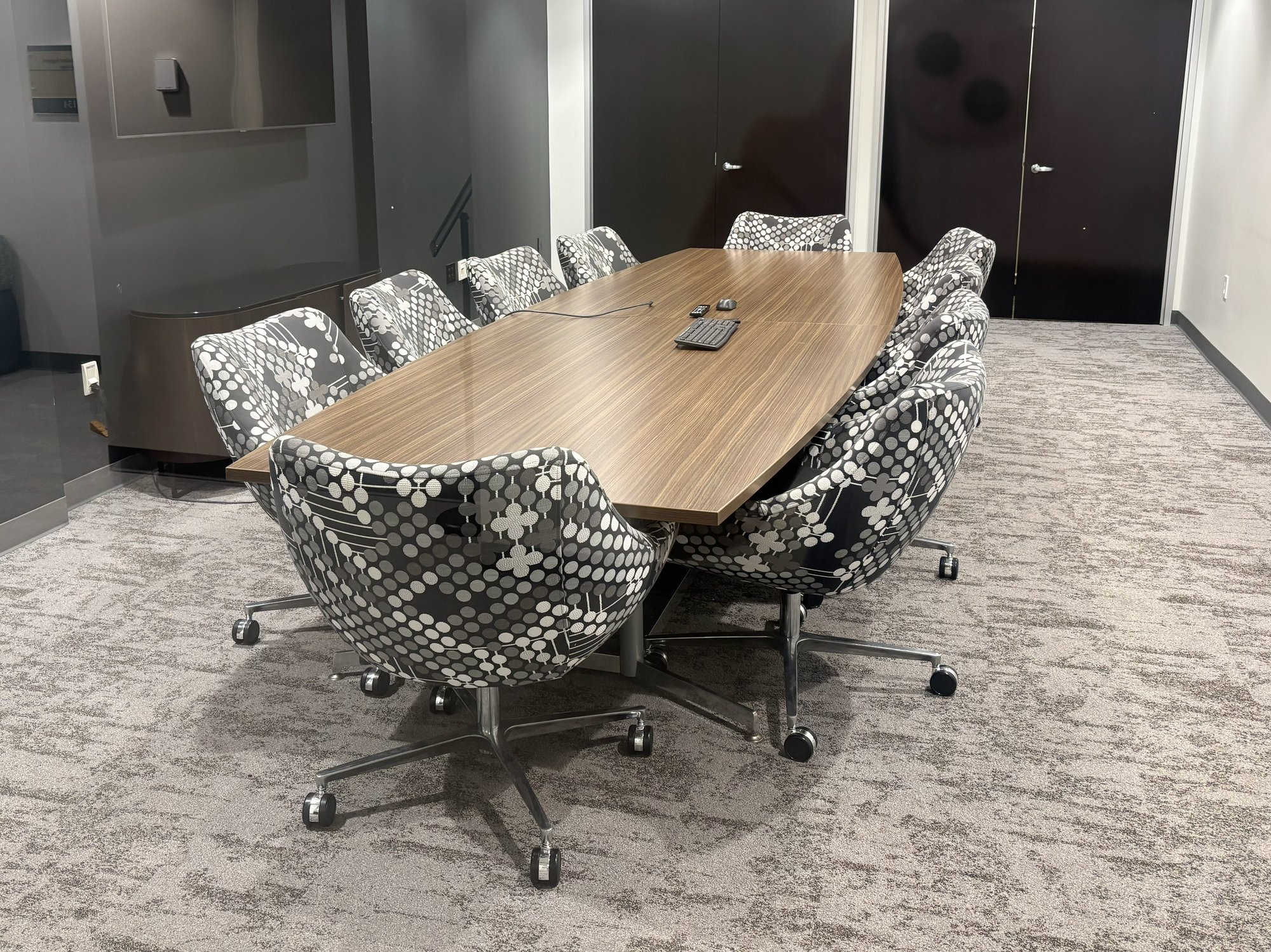 Meeting room with black, grey, and white rolling chairs around a boat-shaped conference table Meeting room with black, grey, and white rolling chairs around a boat-shaped conference table