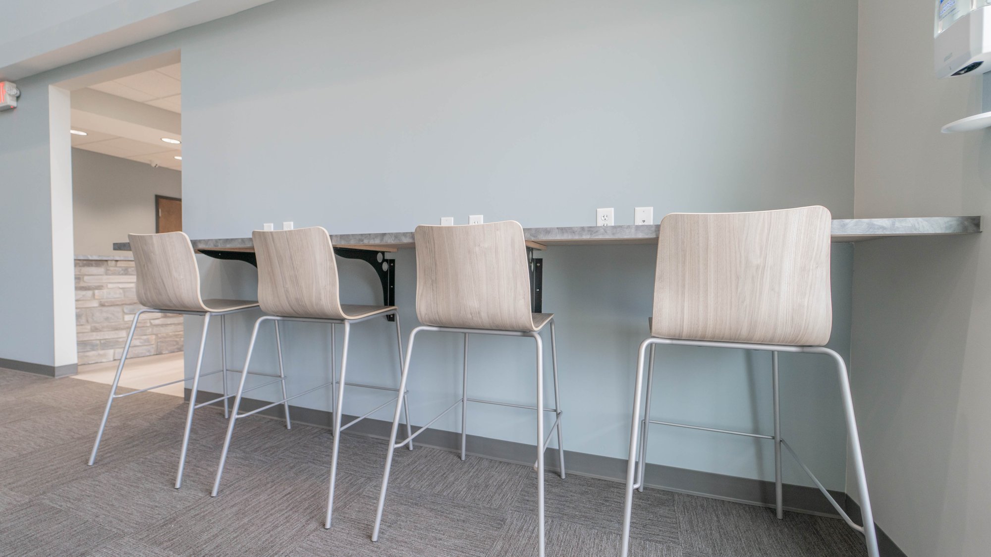 Four counter-height chairs sit pushed underneath a counter attached to the wall Four counter-height chairs sit pushed underneath a counter attached to the wall