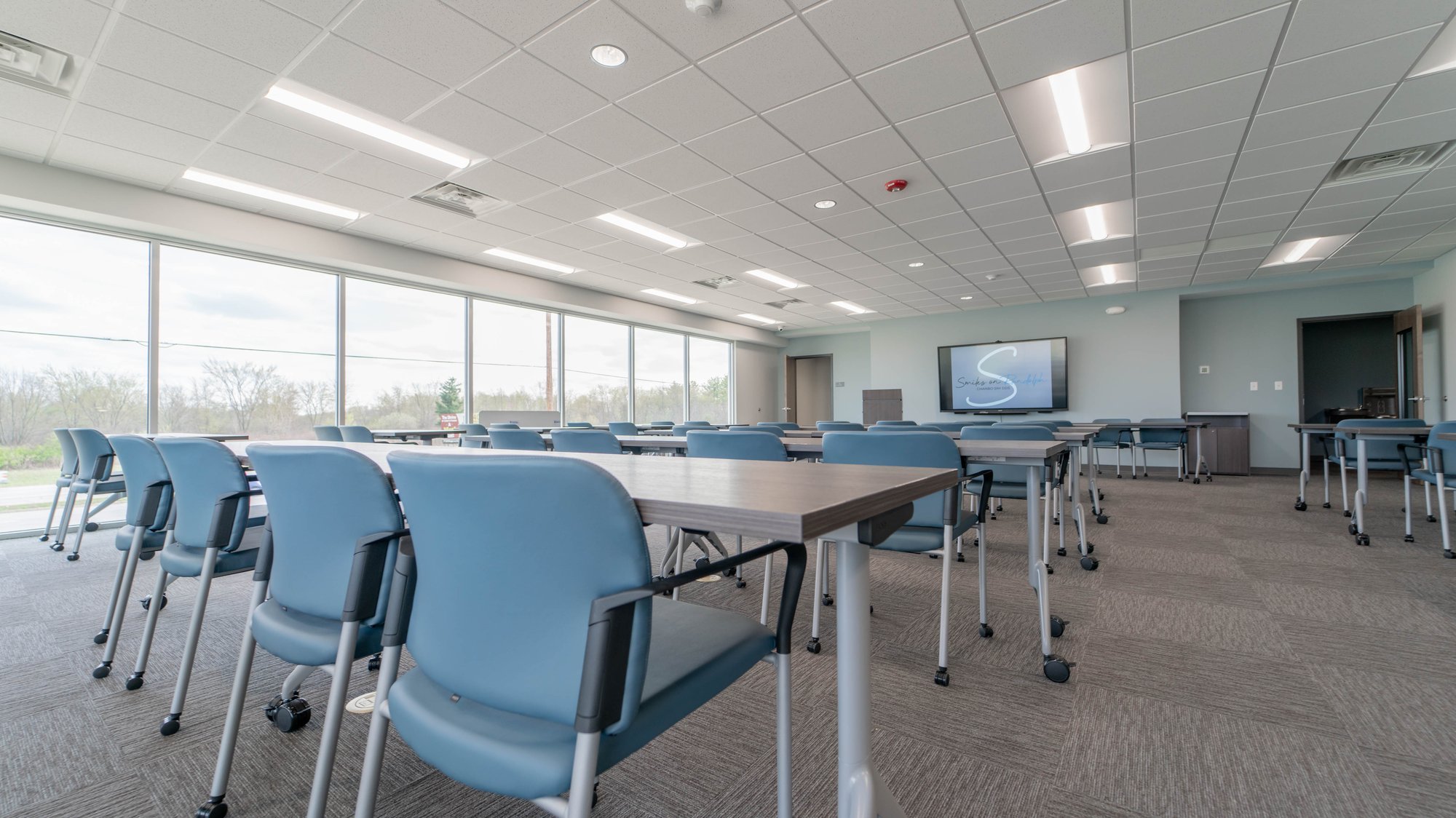 Instruction and presentation facility with many blue rolling chairs and rolling tables Instruction and presentation facility with many blue rolling chairs and rolling tables