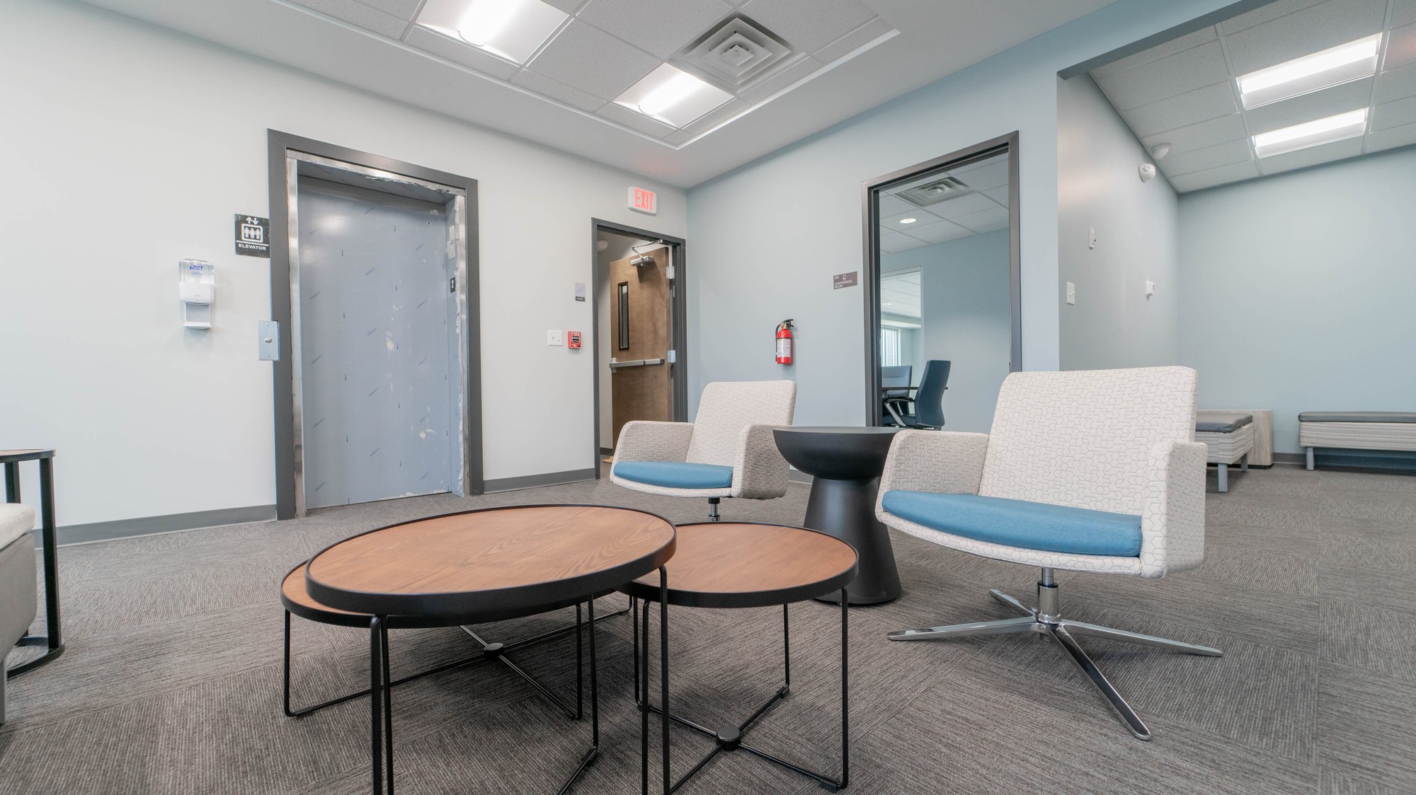 Waiting room with tiered table, and two chairs with blue seats Waiting room with tiered table, and two chairs with blue seats