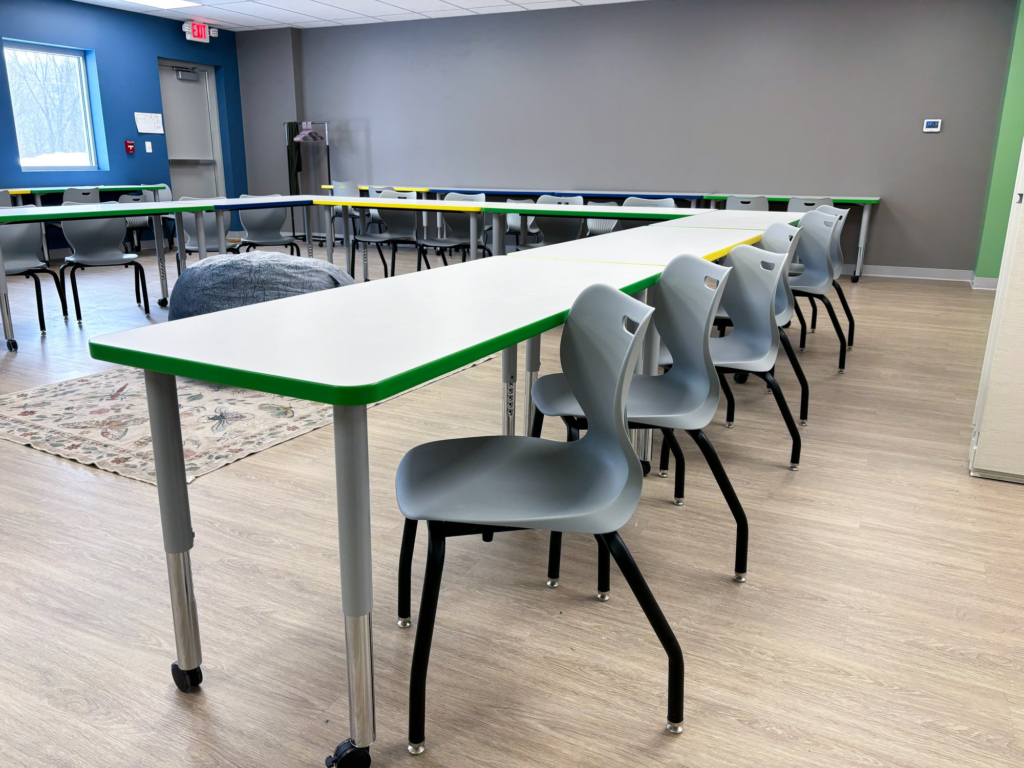 Tables with colorful edge banding, arranged in a "U" shape with chairs surrounding