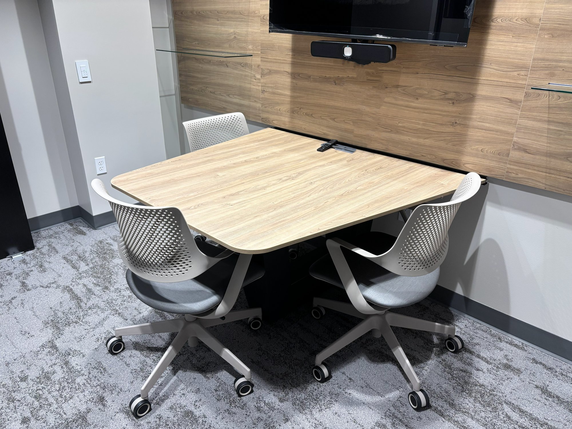 Three rolling chairs sit around an island attached to the wall in a small study room Three rolling chairs sit around an island attached to the wall in a small study room