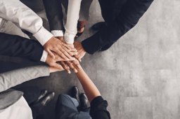 Employees stacking their hands on top of one another, representing teamwork and buy-in