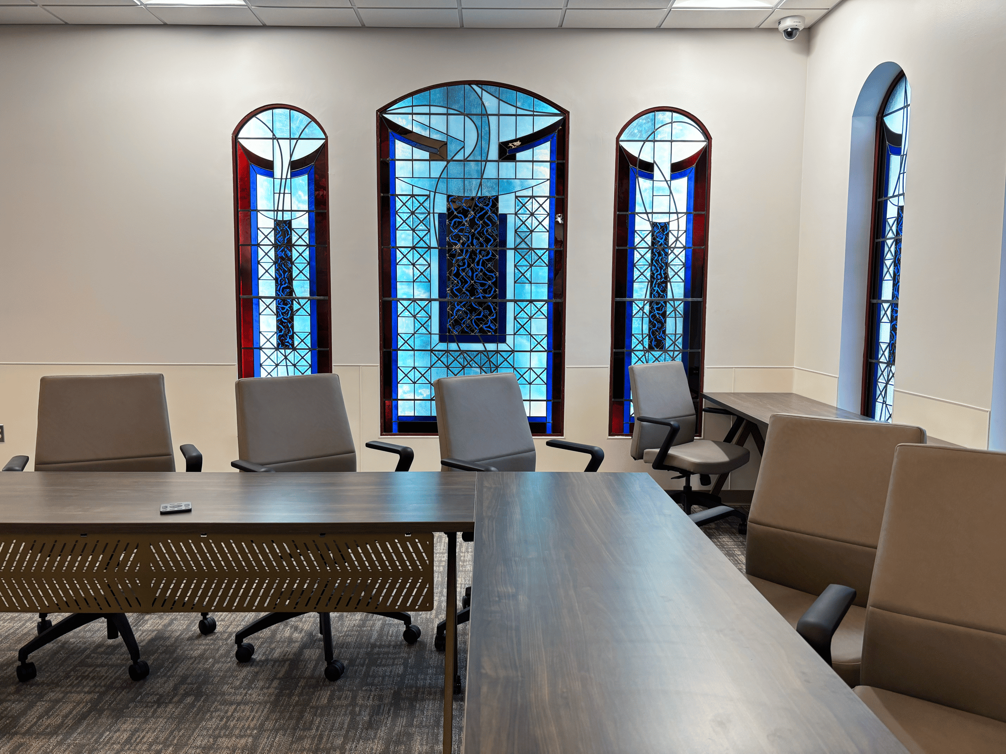 Chairs surround tables backed by stained-glass windows