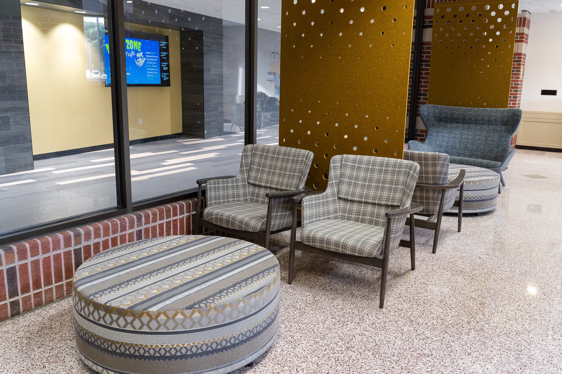 Relaxed chairs sit next to a window and in front of a gold board with holes. Relaxed chairs sit next to a window and in front of a gold board with holes.