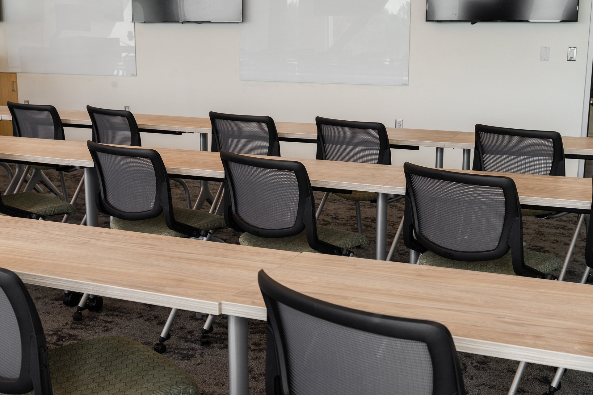 Rolling, mesh-backed chairs pushed into long tables Rolling, mesh-backed chairs pushed into long tables