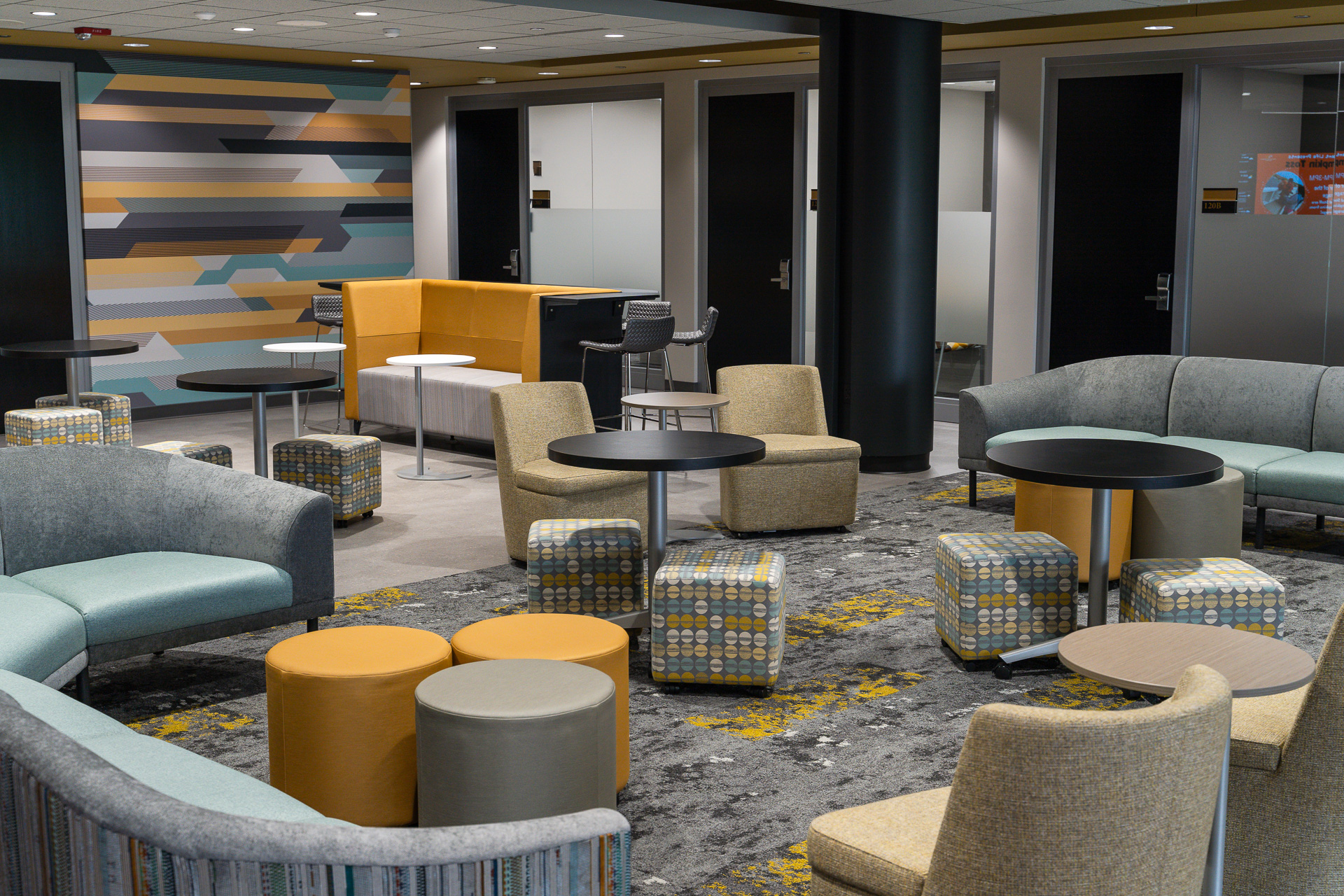 A mix of gray, teal, yellow, and mustard furniture pieces with black tables