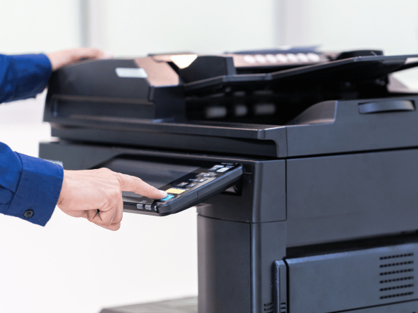 A person pressing a button on a multifunctional printer (mfp) that is part of a managed print services program
